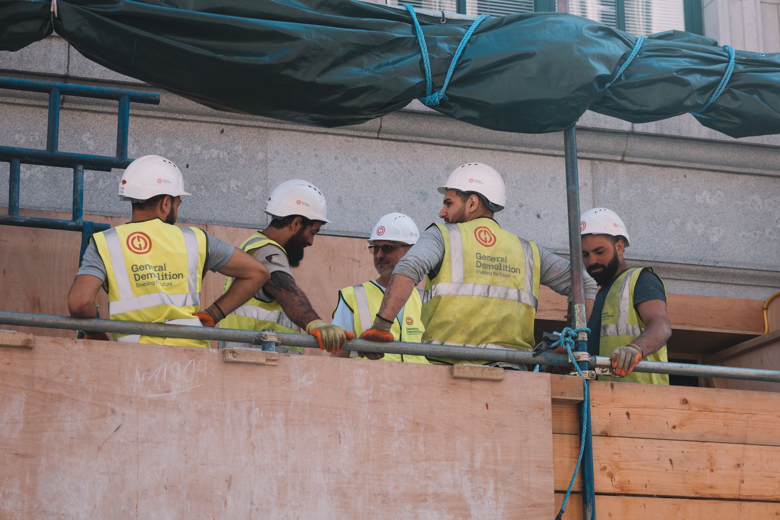 A crew in matching branded hi-viz vests and hard hats on site